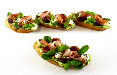 Avokádový chlebíček na celozrnné vece s fíky, Schwarzwaldskou šunkou, mozzarellou, zdobený pistáciemi, bazalkou, černým sezamem a balsamicem (1,7,8,9)
